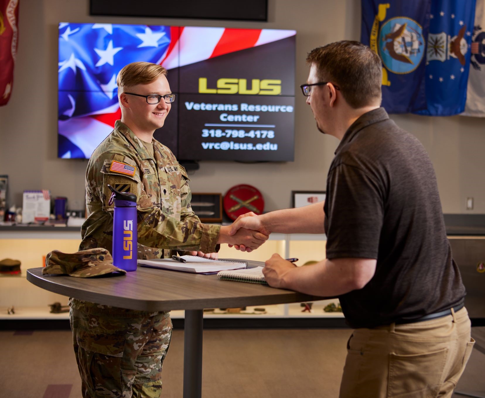 military member shakes hand of lsus veterans recourse center representative