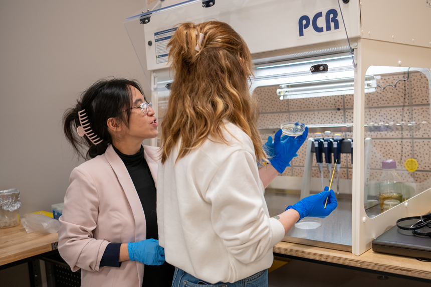 Dr. Vonny Salim assists one of her students in the Cyber Collaboratory